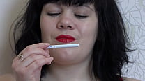 A girl in high-heeled sandals fucks with a big rubber dick. She then smokes with bright red lips.